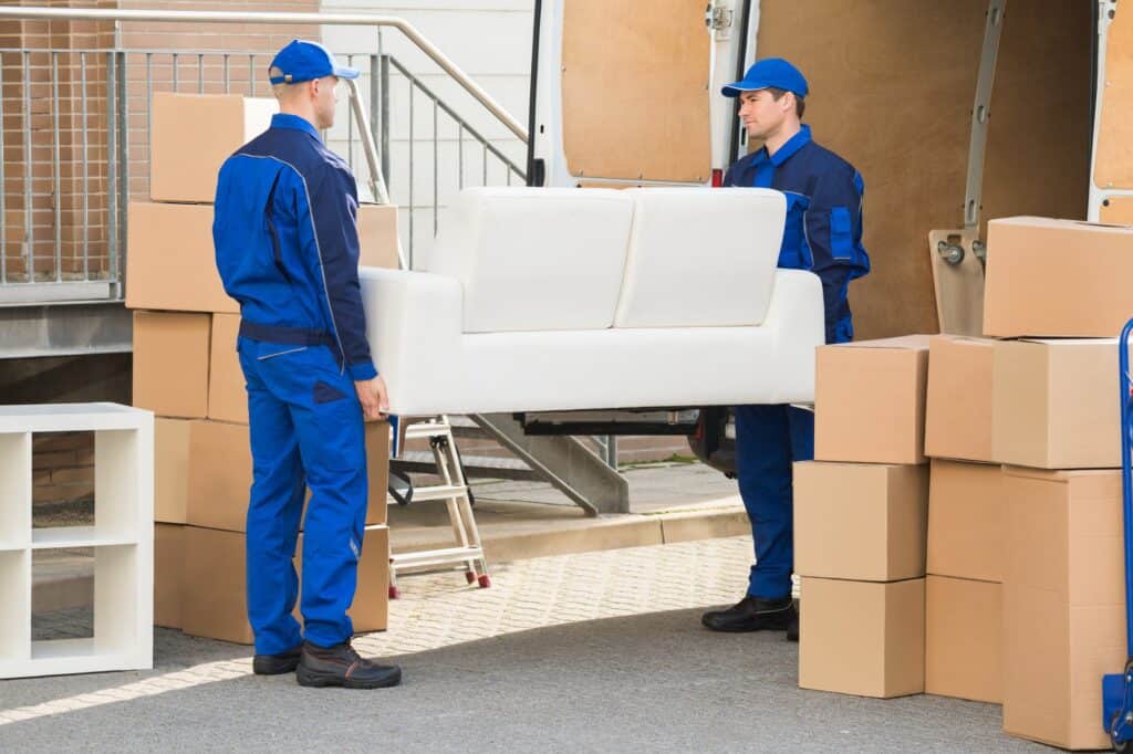 The movers are placing the sofa inside the van in the concept of house move.