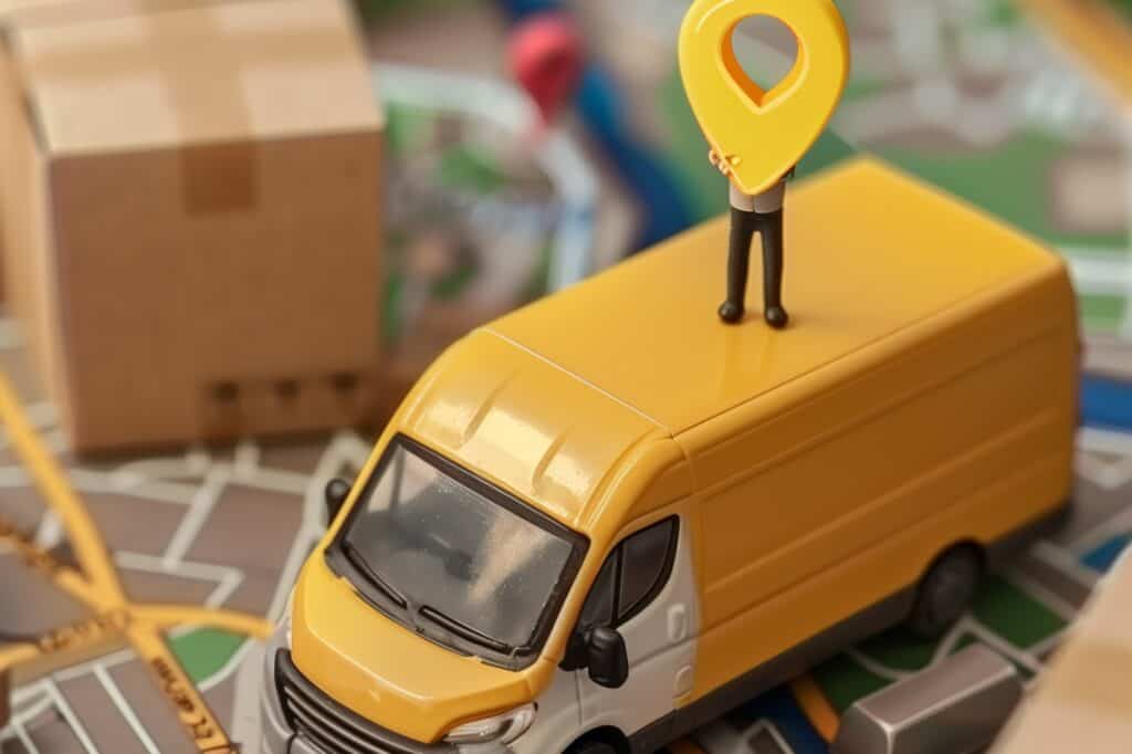 A miniature van on a city map with a miniature man holding a locator pin in the concept of man-and-van in Dulwich.