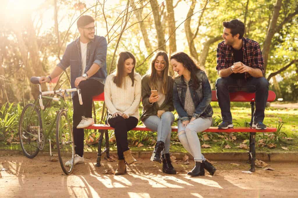 Group of friends sitting on a bench in a park in the concept of 'best parks and green spaces in Dulwich'.