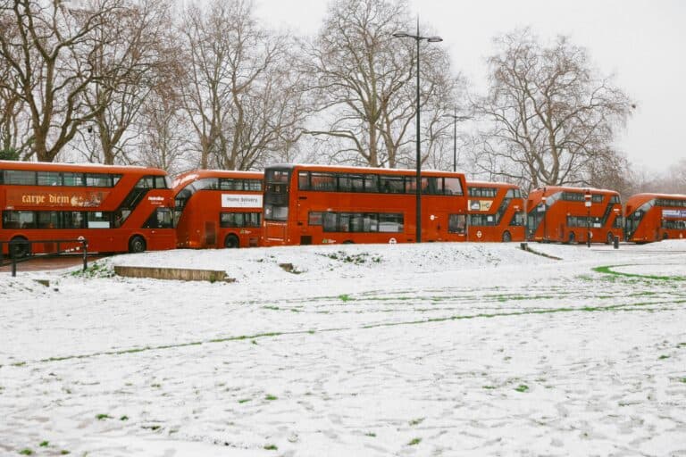 Parked double-decker buses on a snowy ground in the concept of 'how to use Dulwich's public transport'.