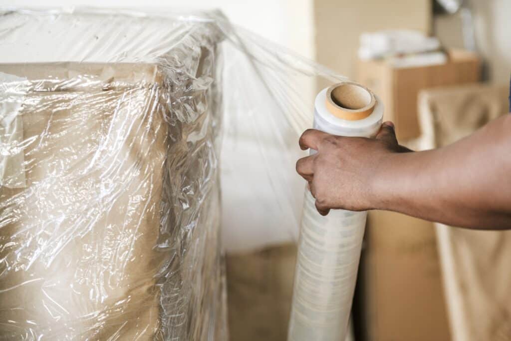 Cropped image of a professional packer wrapping a huge cardboard